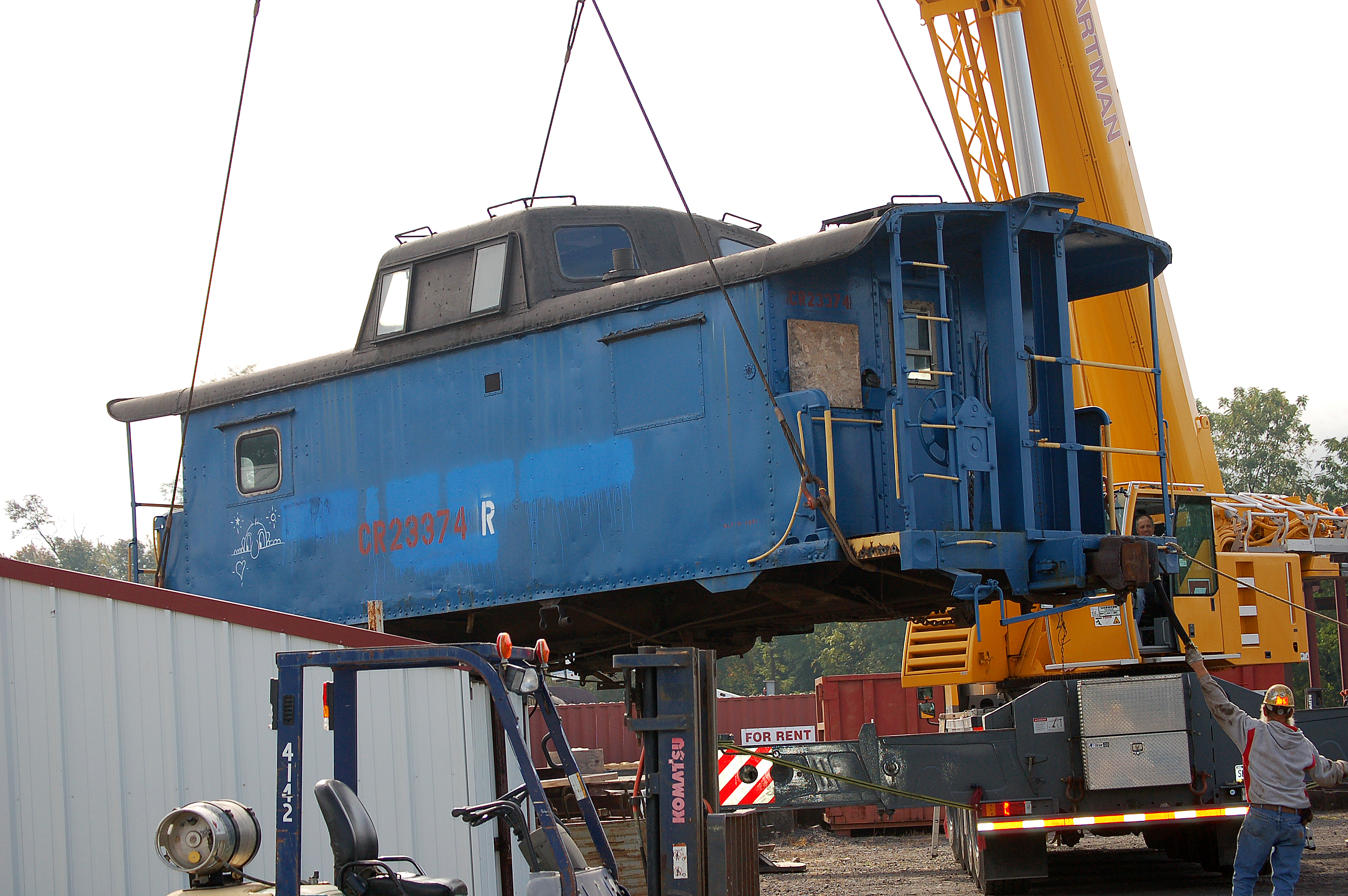 A rail car is lifted from the tracks to a trailer bed. Rent a crane from Zartman Construction for any of your lifting needs.